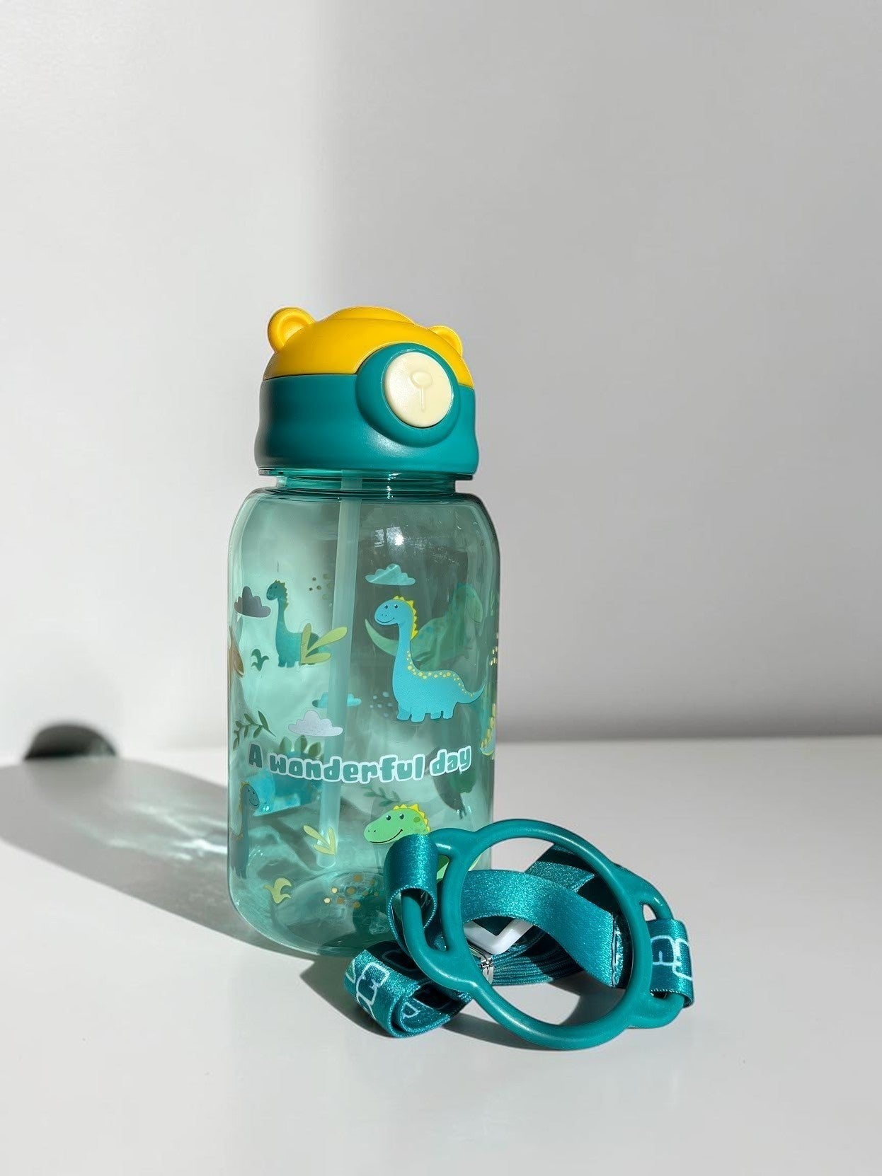 Botella de agua Vamos Niños azul translúcida con estampado de dinosaurios, pajita y correa ajustable para niños.