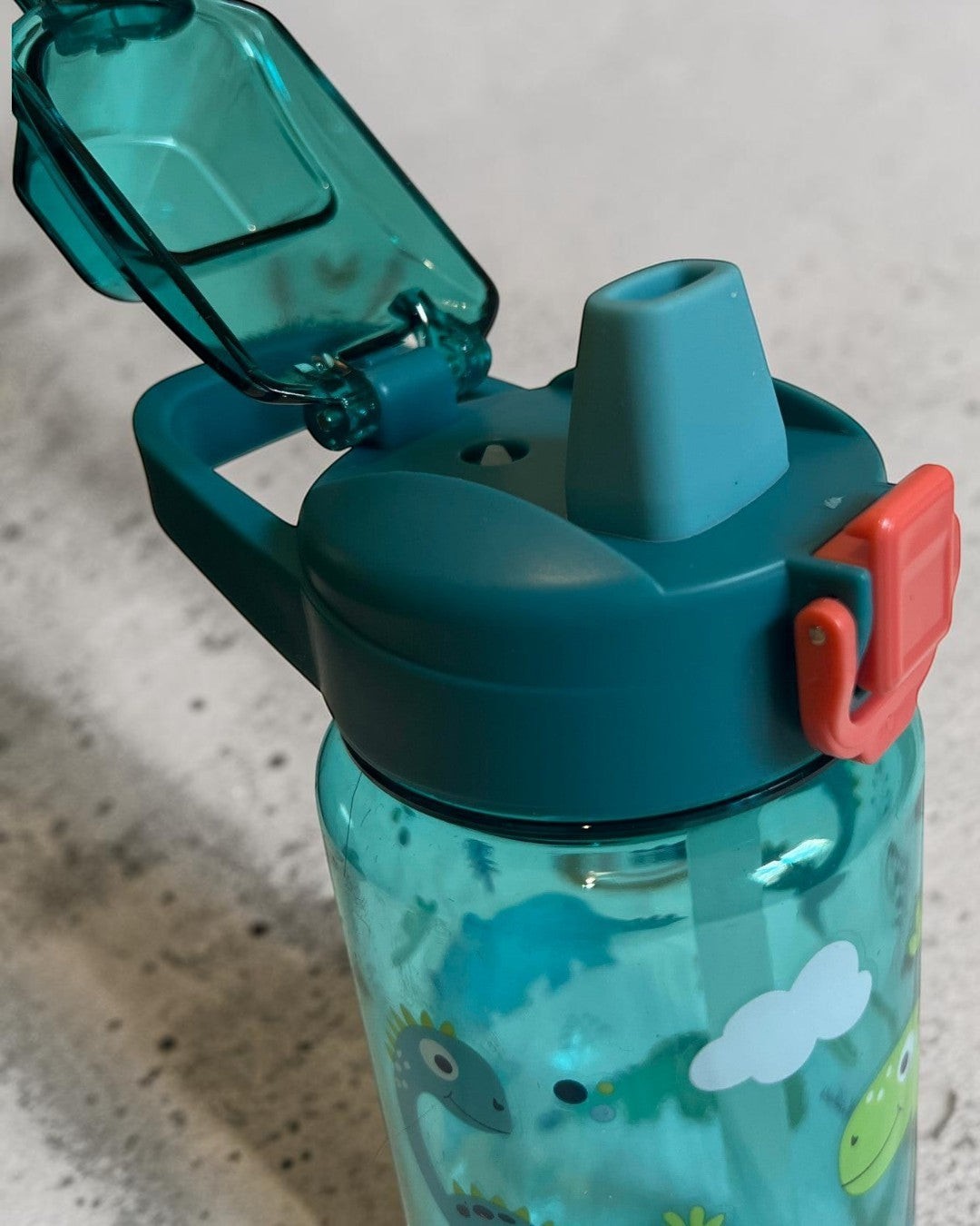 Botella de agua infantil Vamos Niños de 600 ml con estampado de dinosaurios, boquilla de silicona y tapa abatible verde.