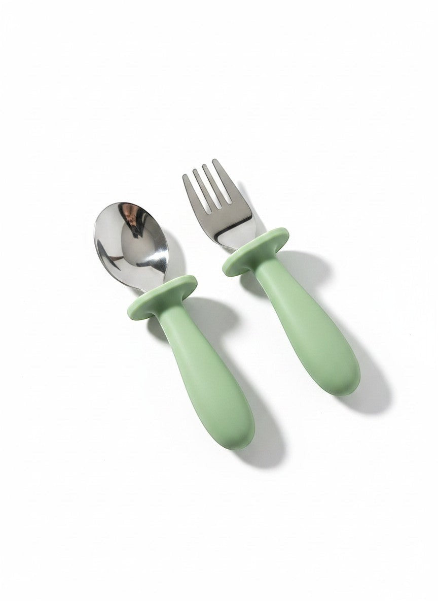 Set de cubiertos para bebé Vamos Niños de acero inoxidable y silicona verde salvia, con mangos ergonómicos para autoalimentación.