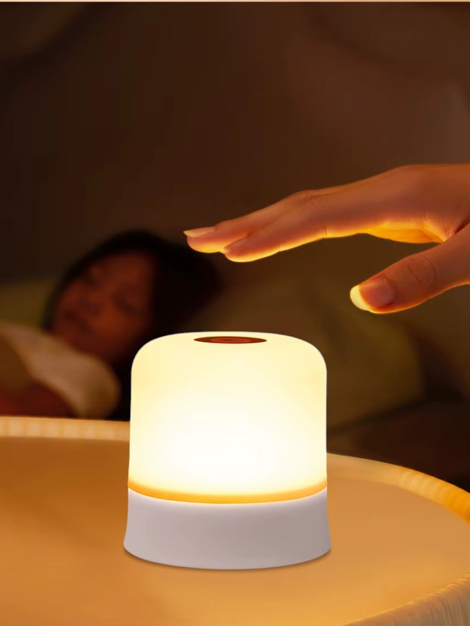 Luz nocturna LED Vamos Niños portátil con control táctil y luz cálida regulable sobre una mesa de noche