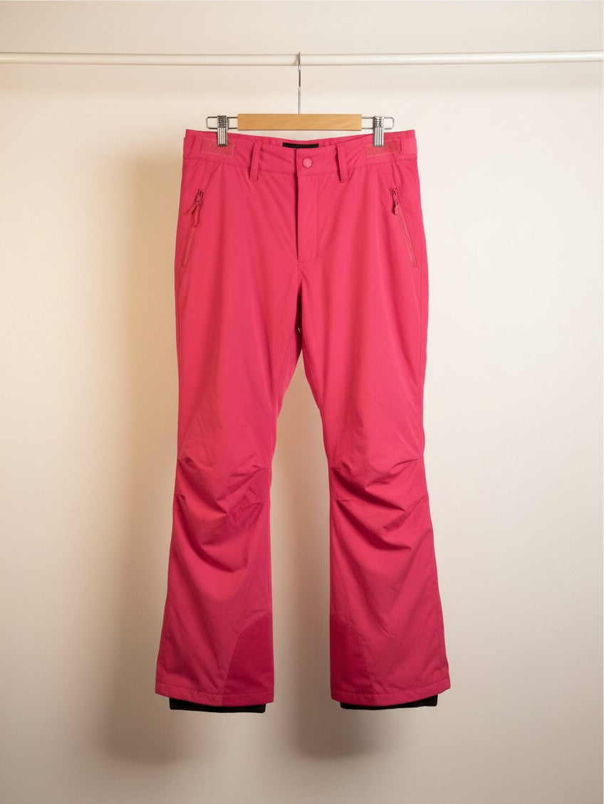 Pantalones de esquí Vamos Niños de color rosa vibrante con bolsillos frontales y polainas integradas para nieve.