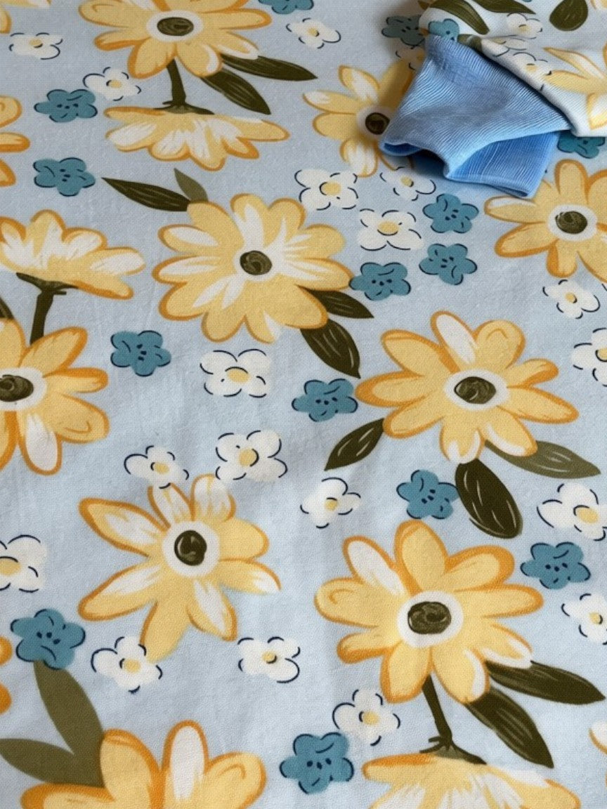 Pijama infantil Vamos Niños azul claro con estampado de flores amarillas y detalles en canalé en cuello y puños.