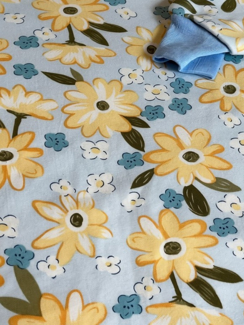 Pijama infantil Vamos Niños azul claro con estampado de flores amarillas y detalles en canalé en cuello y puños.