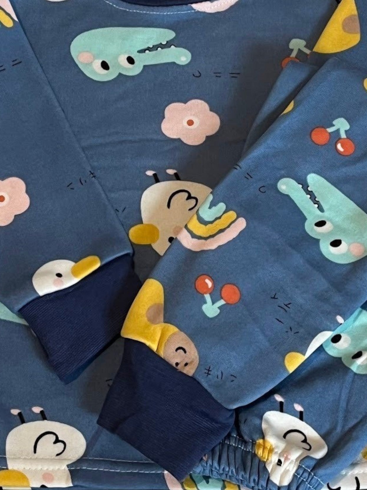 Pijama afranelado Vamos Niños azul con estampado de animalitos, flores y cerezas, con puños elásticos en las mangas.