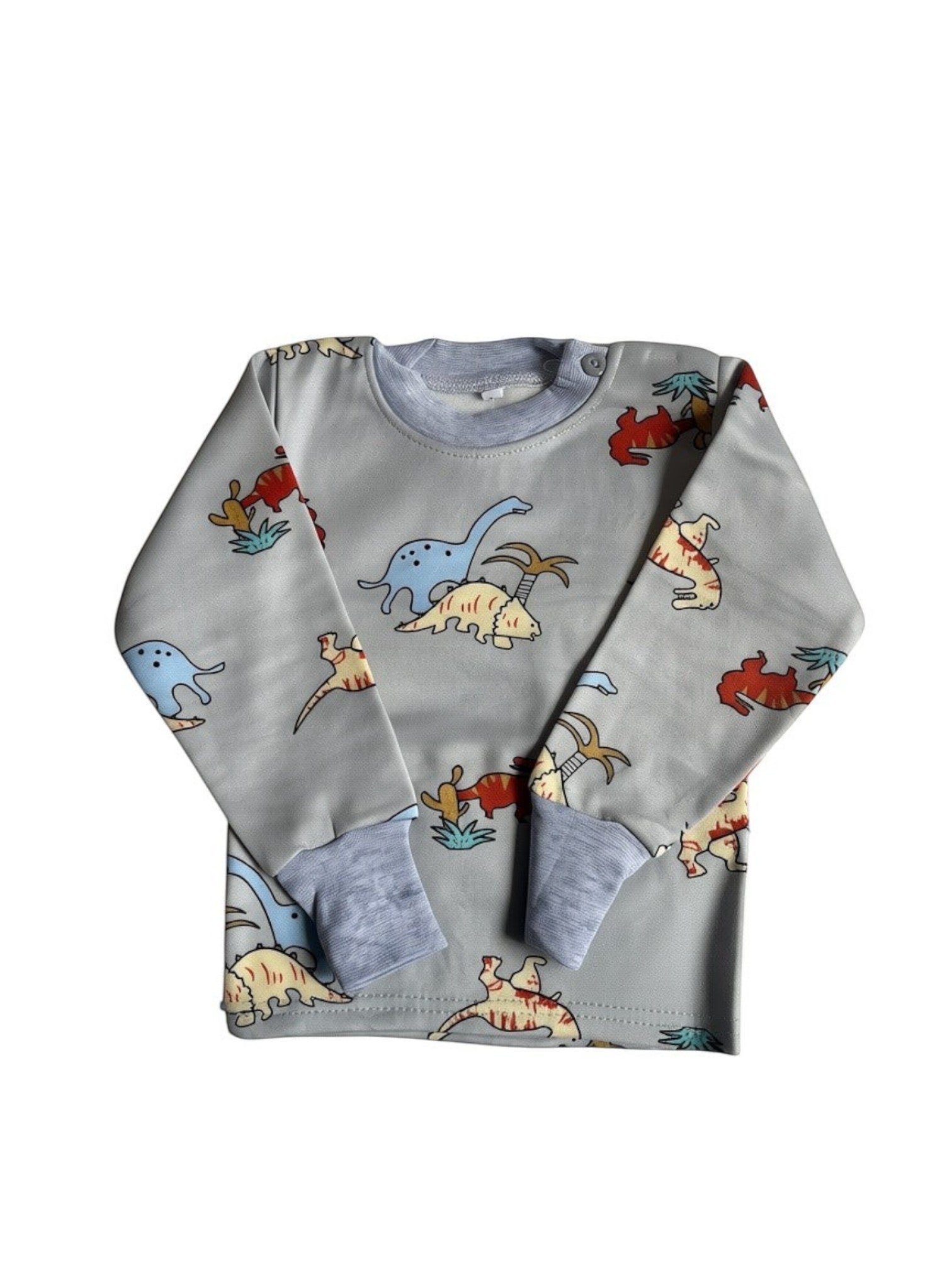 Pijama afranelado Vamos Niños gris con estampado de dinosaurios coloridos, manga larga y puños elásticos suaves.