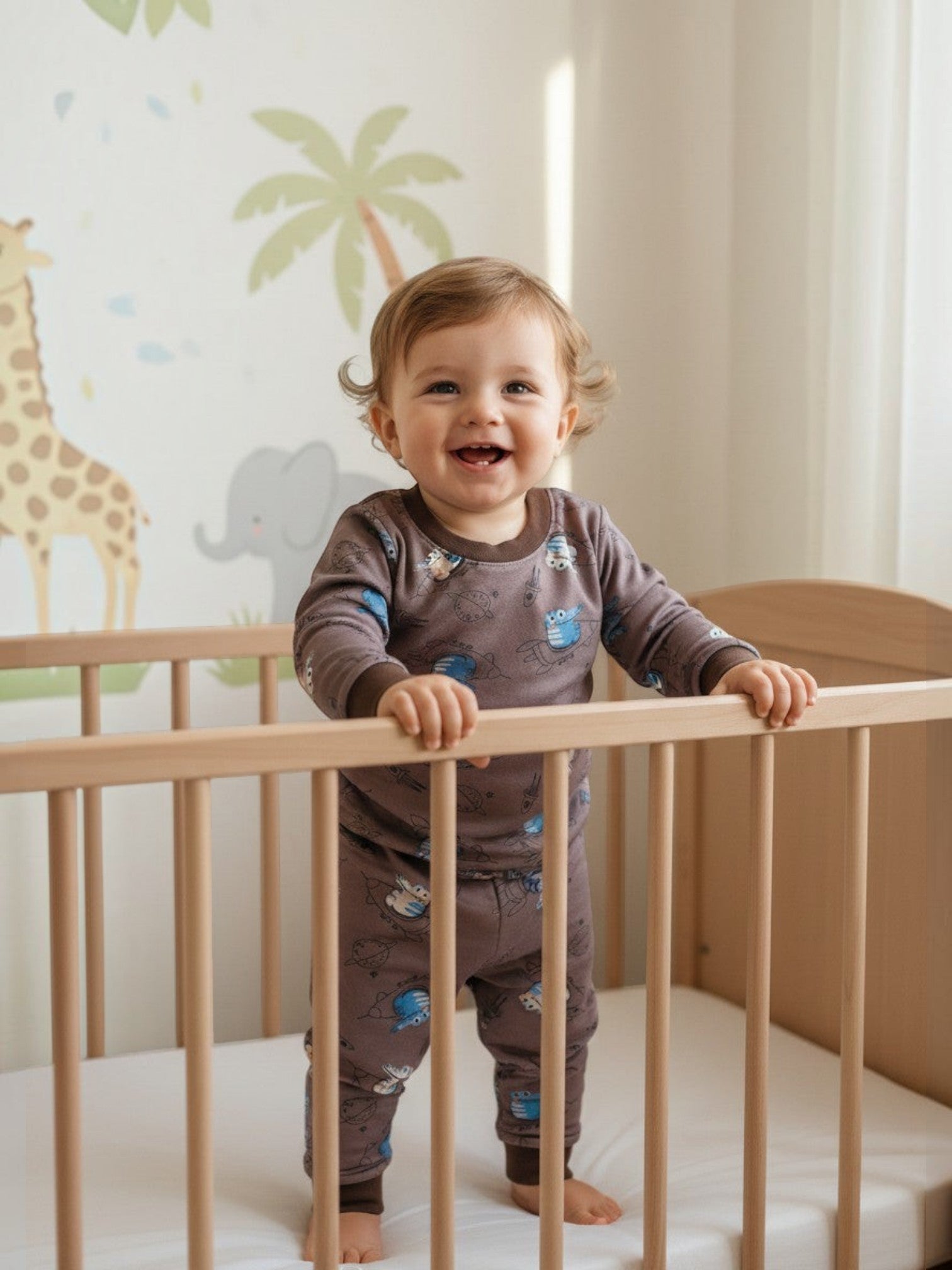 Bebé sonriente en cuna vistiendo pijama afranelado café con estampado de dinosaurios de Vamos Niños