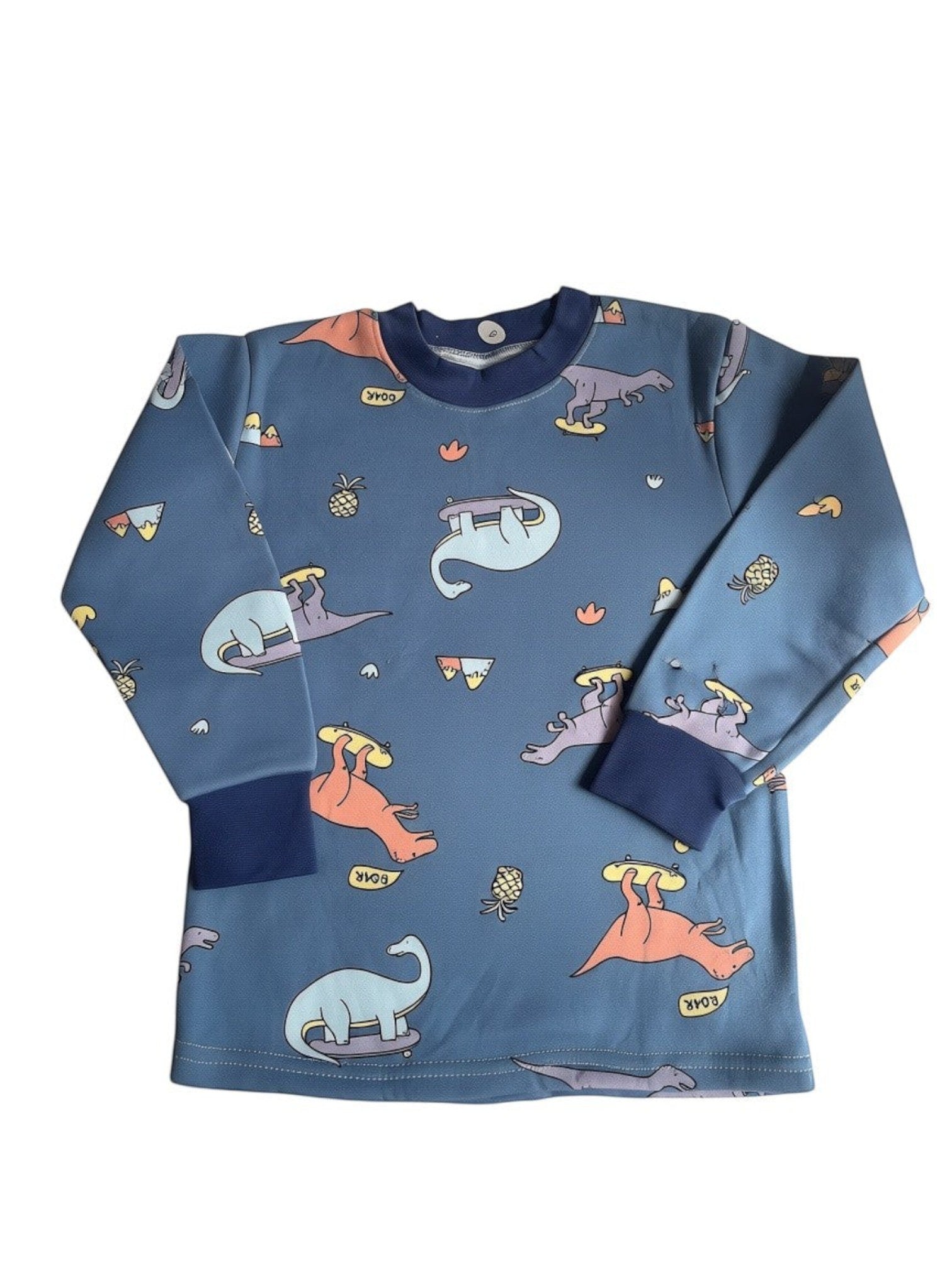 Pijama Vamos Niños azul de manga larga con estampado de dinosaurios patinadores y piñas, tejido suave y cómodo.