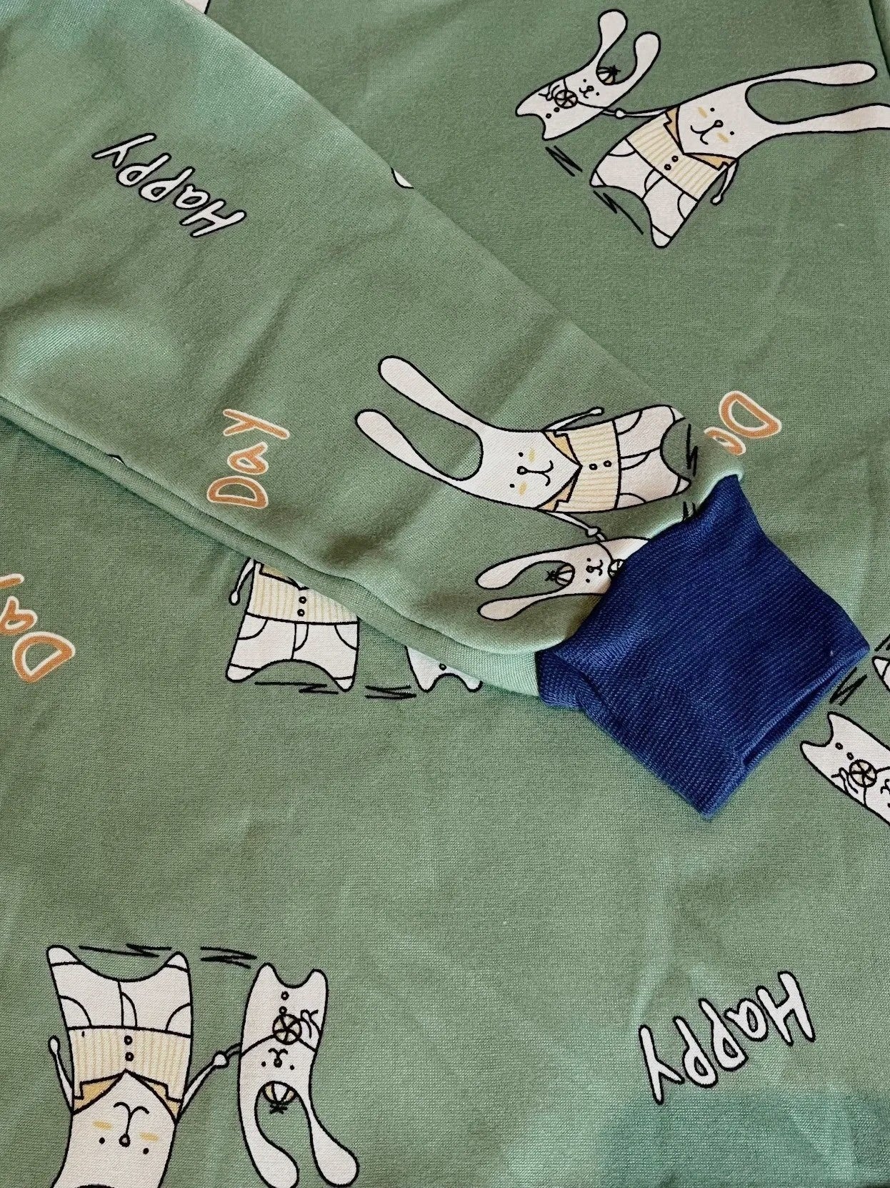 Pijama infantil Vamos Niños verde con estampado de conejitos y texto Happy Day, puños elásticos en azul marino.