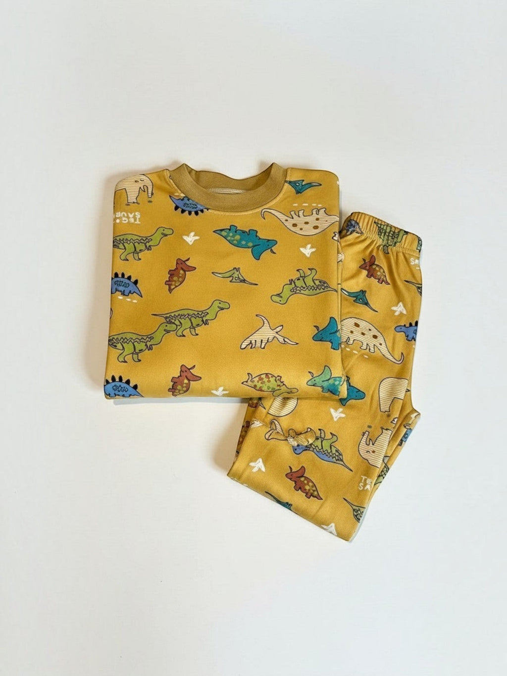 Conjunto de pijama Vamos Niños color mostaza con estampado de dinosaurios, camiseta manga larga y pantalón cómodo.