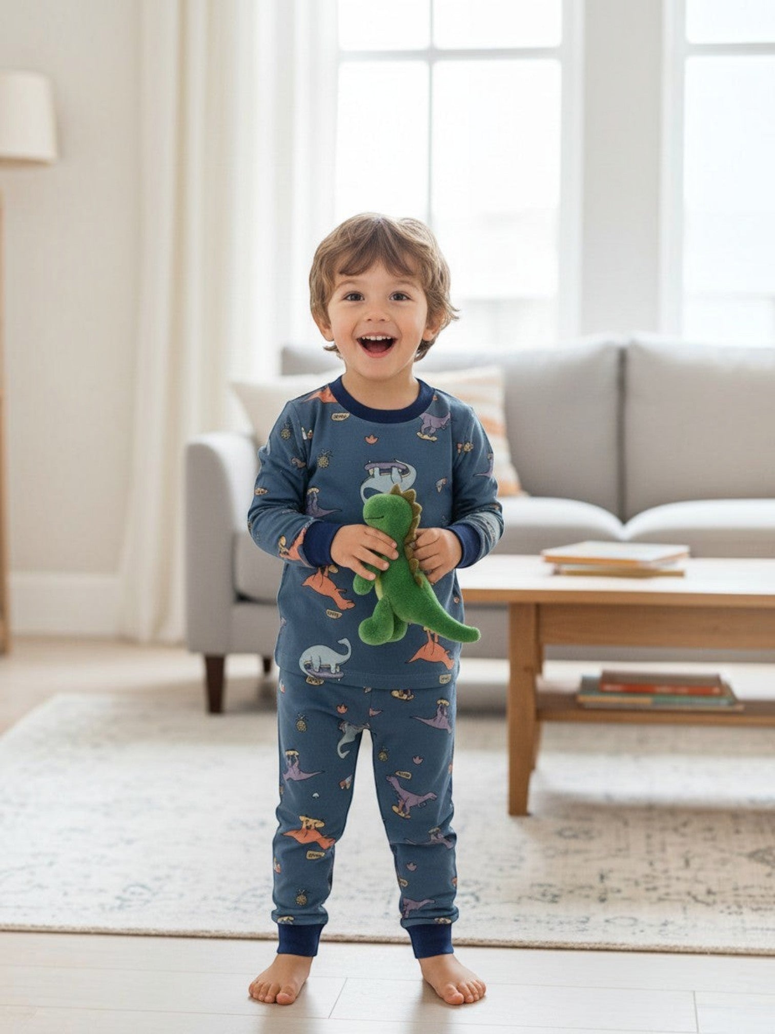 Niño feliz con pijama azul Vamos Niños de dinosaurios patinadores y puños elásticos en una sala de estar luminosa