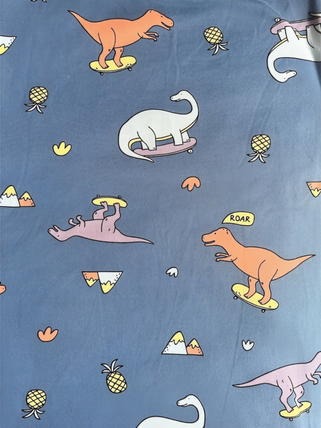 Pijama infantil Vamos Niños con estampado de dinosaurios patinadores y piñas sobre fondo azul suave