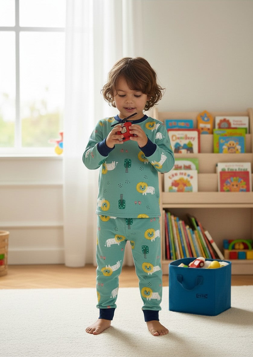Niño jugando con un juguete en una habitación, vistiendo pijama Vamos Niños verde agua con leones.