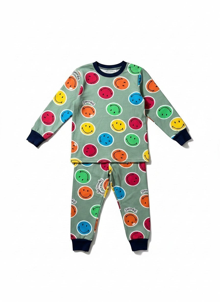 Pijama Vamos Niños con estampado de caras sonrientes coloridas sobre fondo verde y puños azul marino