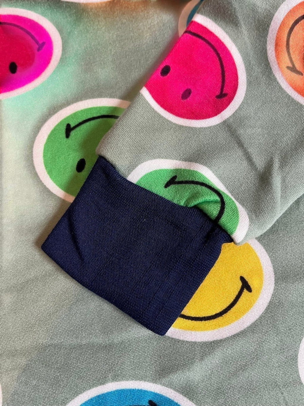 Pijama Vamos Niños con estampado de caras sonrientes coloridas sobre fondo verde suave