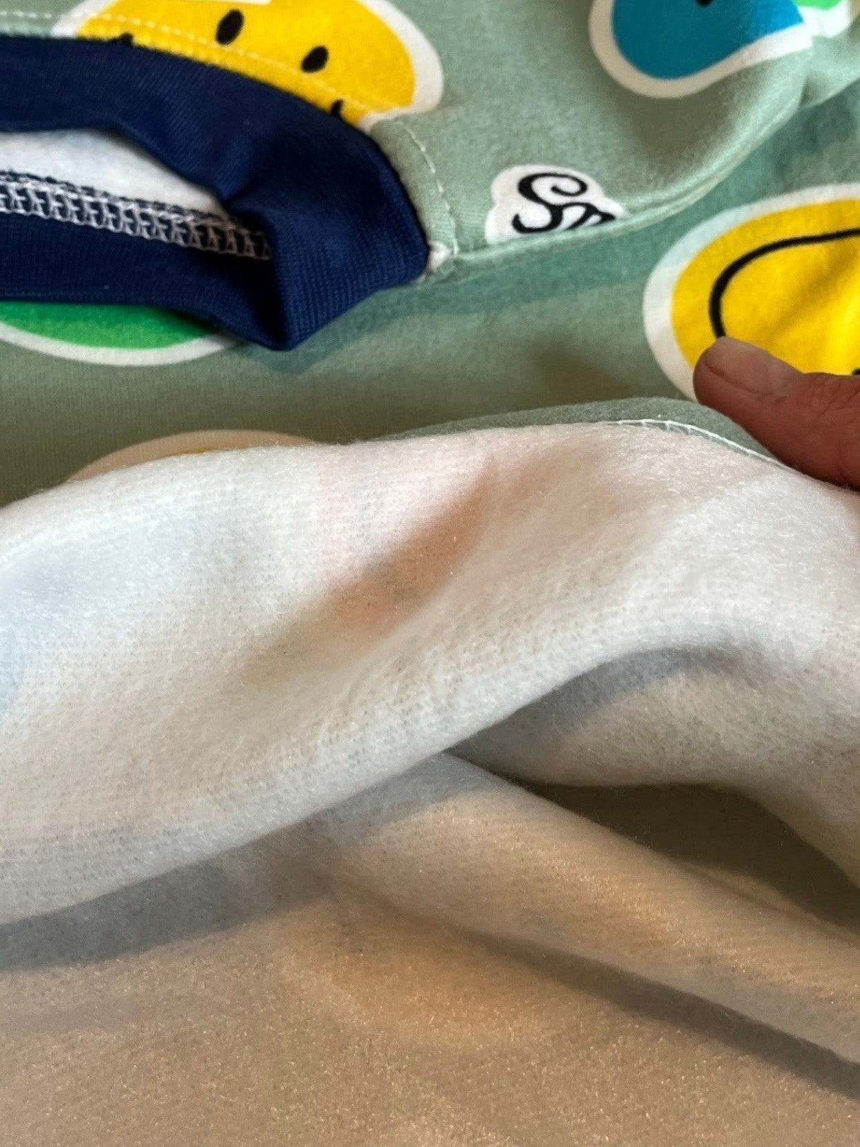 Pijama Vamos Niños con estampado de caras sonrientes, interior de felpa suave y cuello azul marino.