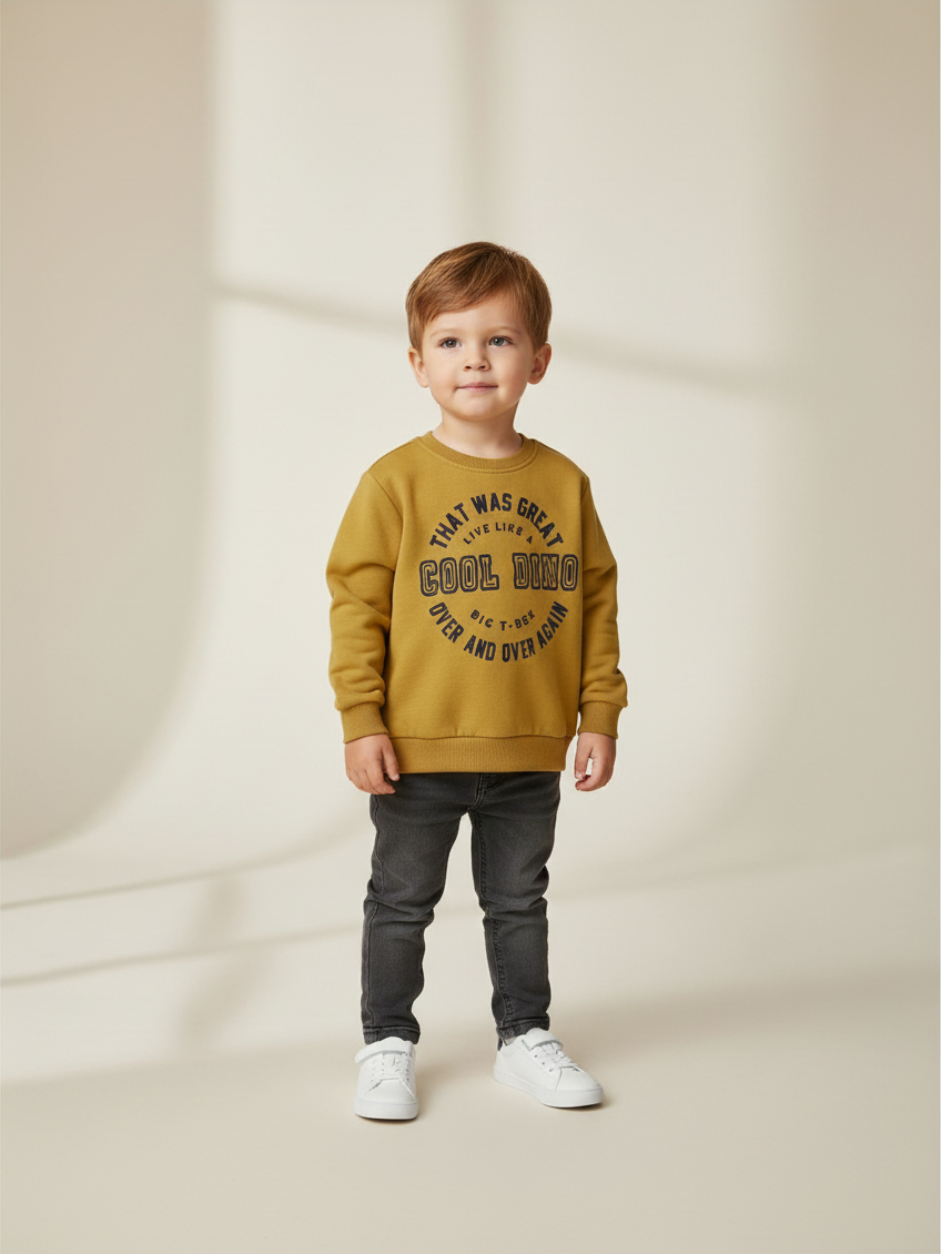 Niño pequeño vistiendo polerón amarillo de Vamos Niños con estampado de letras y dinosaurio, estilo casual.