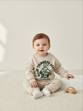 Bebé sentado vistiendo polerón beige con estampado verde de Vamos Niños, estilo casual y cómodo para niños.