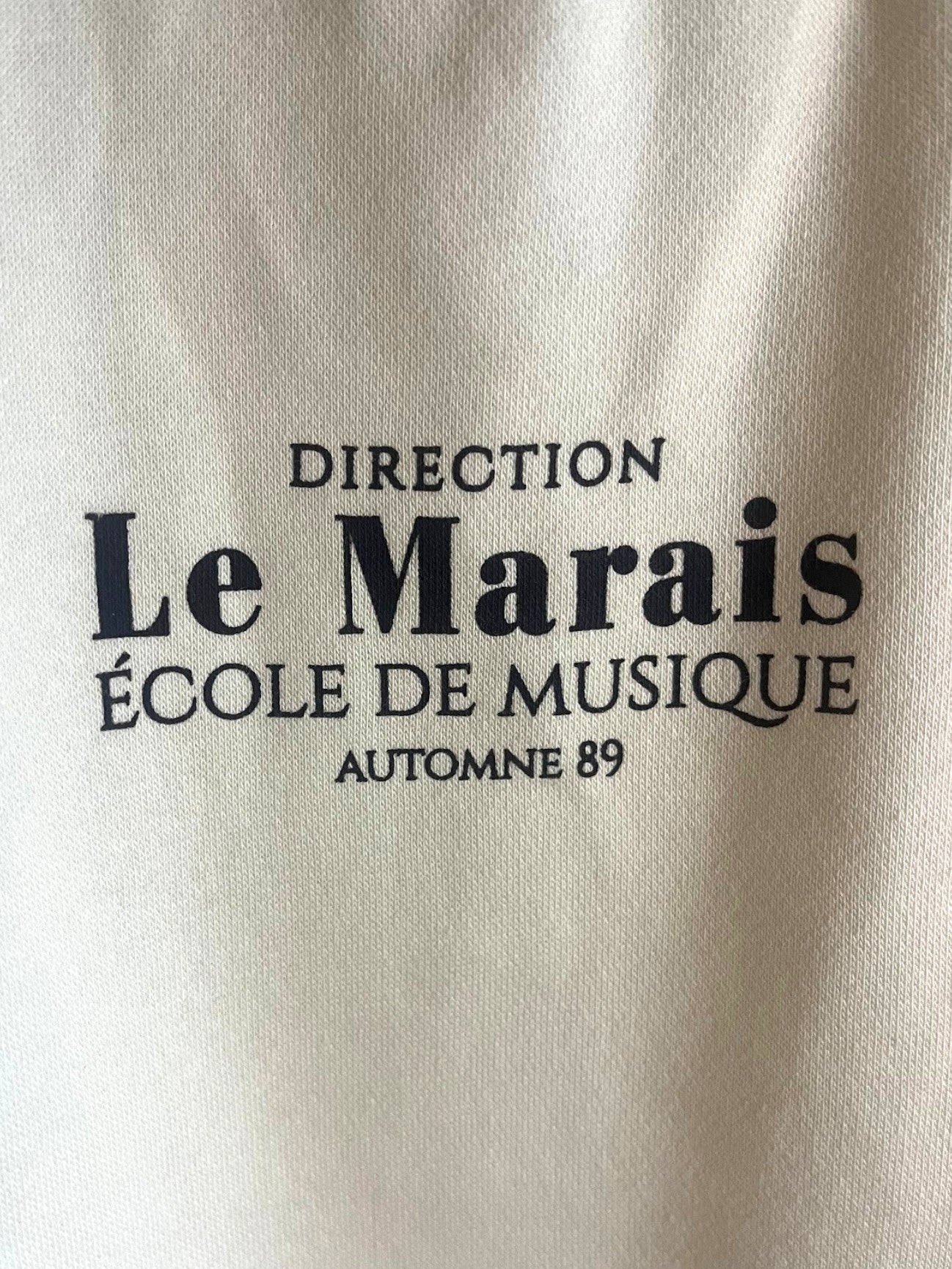 Polerón beige de niña marca Vamos Niños con estampado de letras negras estilo tipográfico