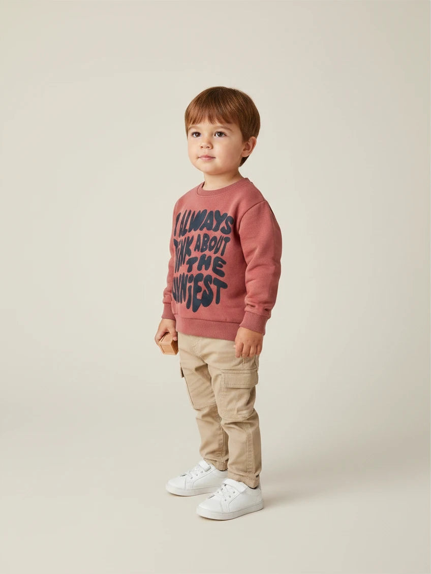 Niño vistiendo polerón terracota Lefties de Vamos Niños con estampado de letras negras y pantalones cargo beige
