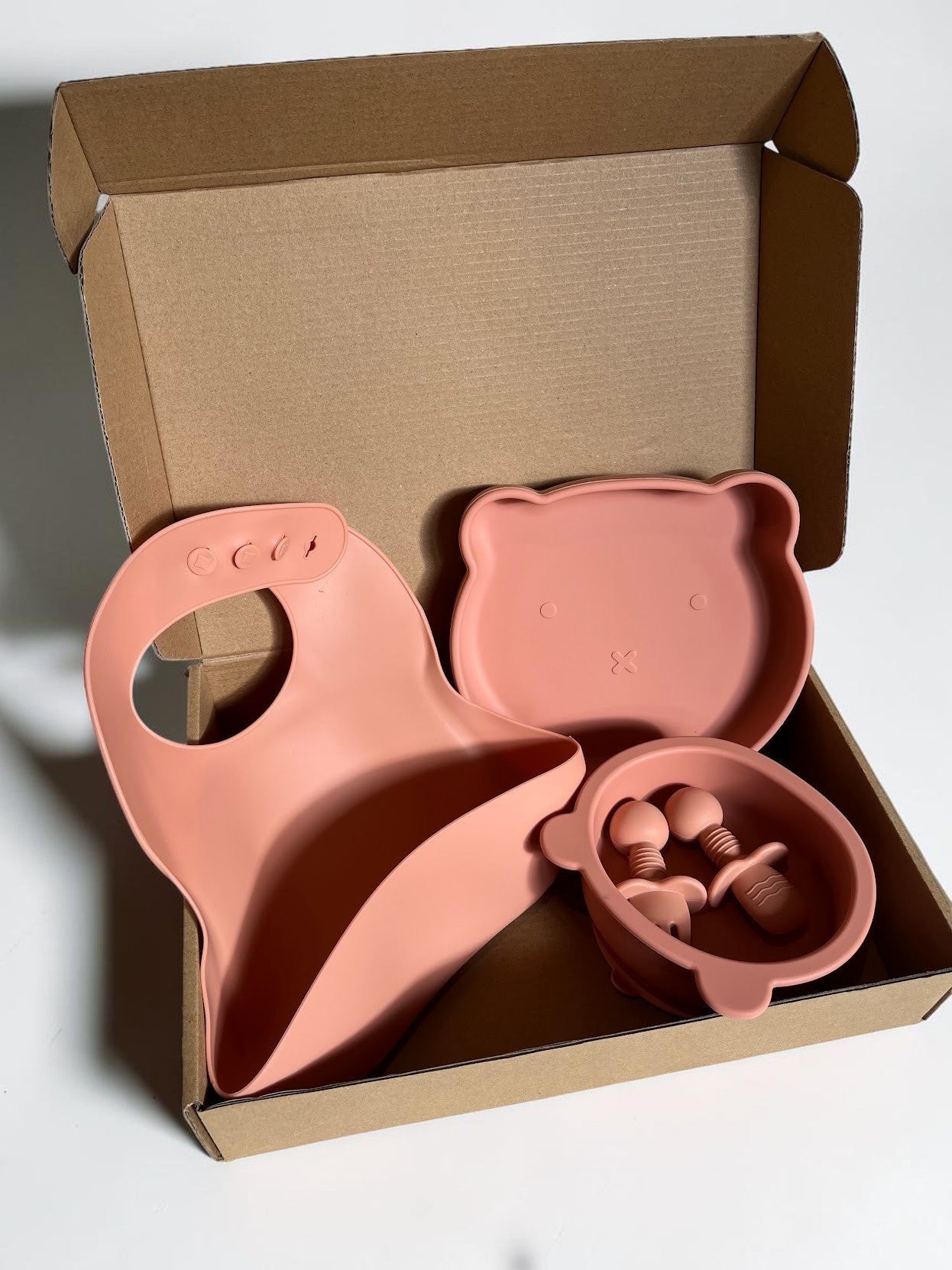 Set de alimentación Vamos Niños de silicona rosa con babero, plato y cuenco con forma de osito y cubiertos para bebé.