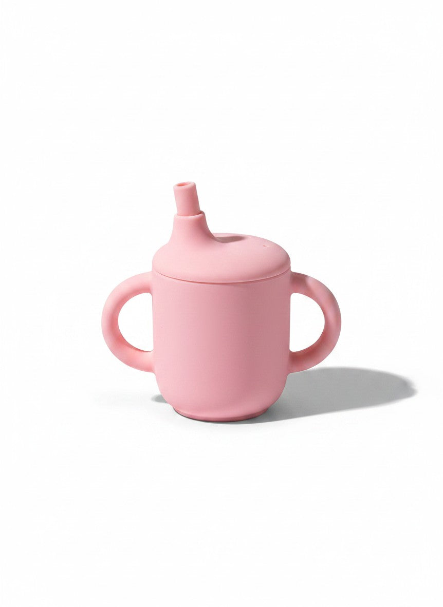 Vaso de aprendizaje Vamos Niños de silicona rosa con dos asas y pajita para bebés, diseño ergonómico y seguro.