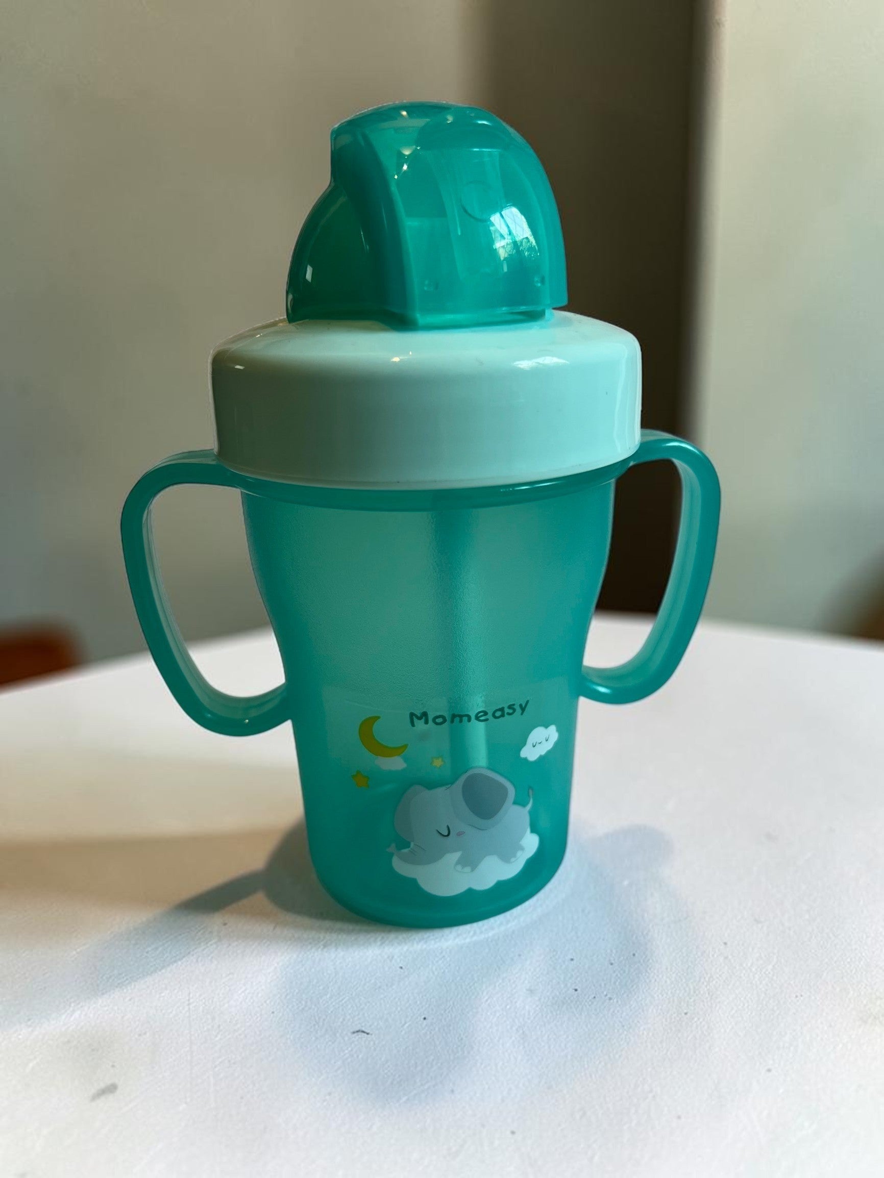 Vaso de aprendizaje verde azulado de Vamos Niños con asas, pajita y diseño de elefante y luna. Plástico.